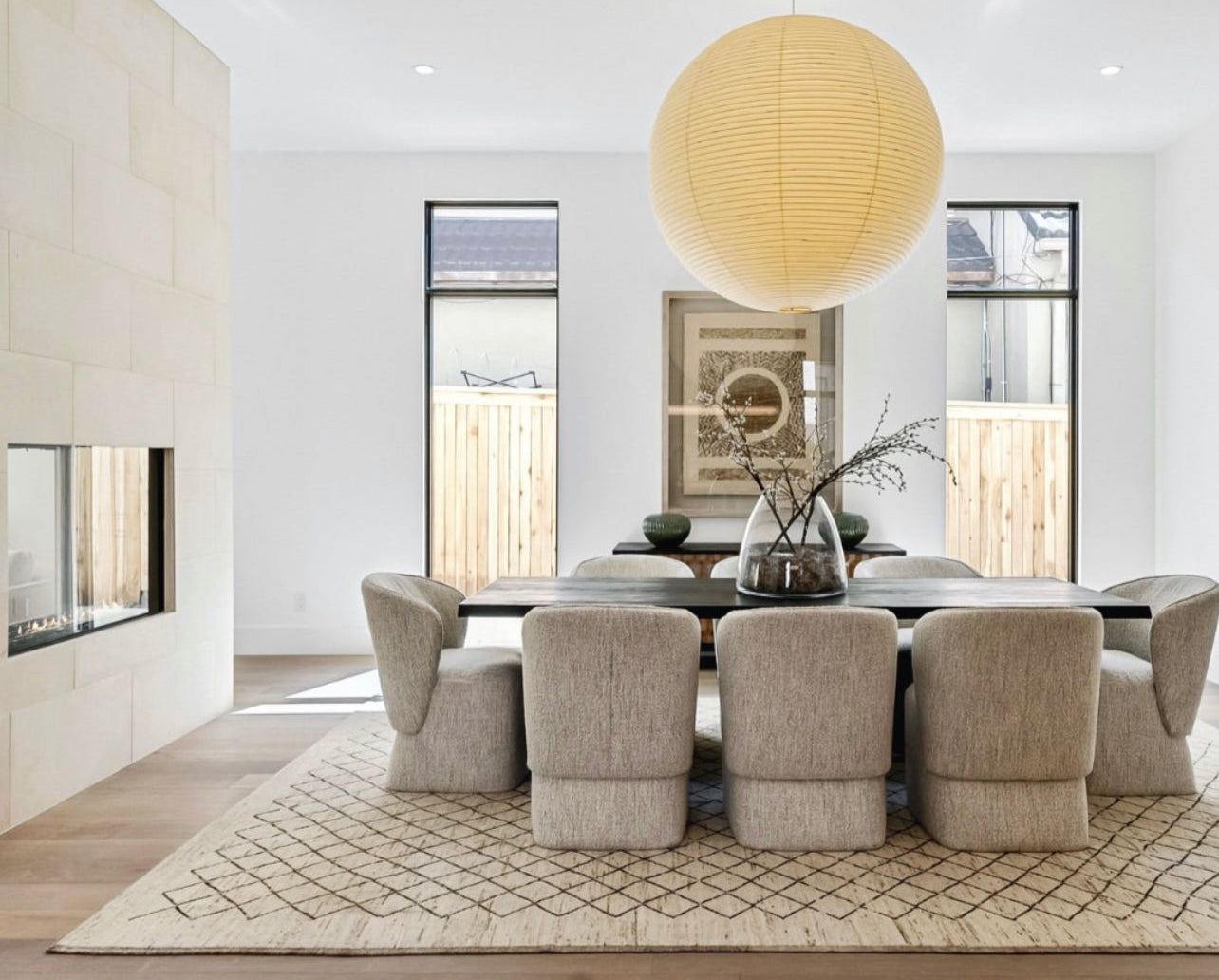 Modern dining room with a long table and chairs, featuring a large round pendant light.