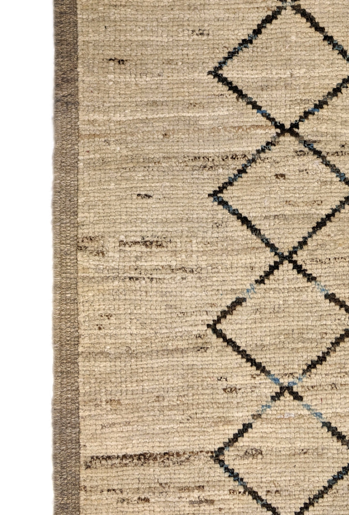 A hand-knotted wool rug with a geometric pattern in beige, brown, blue, and gray tones, featuring a coastal aesthetic. Cozy pile.