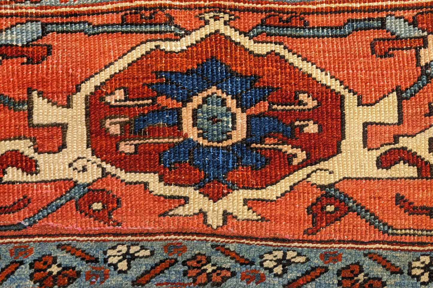 A hand-knotted wool rug with a traditional Serapi design, featuring a luxurious palette of ink blue, warm reds, green, pink, gold, blue, and ivory.