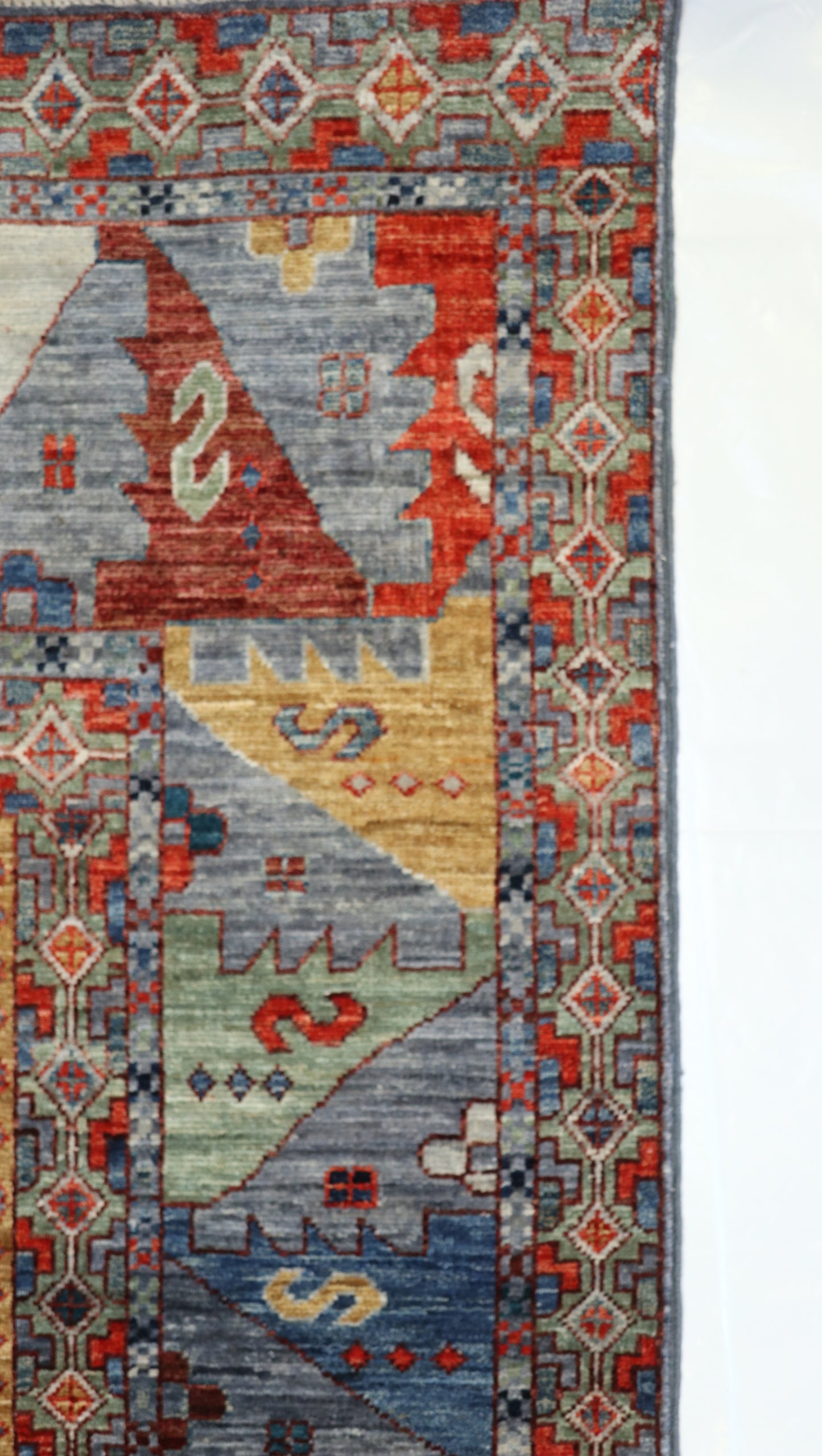 Hand-knotted decorative rug with geometric pattern with bluish-gray base sea glass blues and greens warm red and golden beige tones.