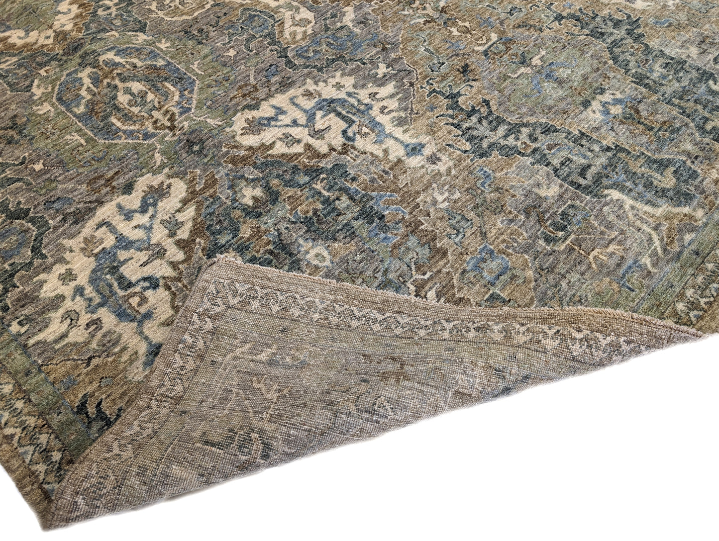 A hand-knotted wool rug featuring a traditional coastal lifestyle design with beige, blue, green, brown, gold, ivory, and grey colors.