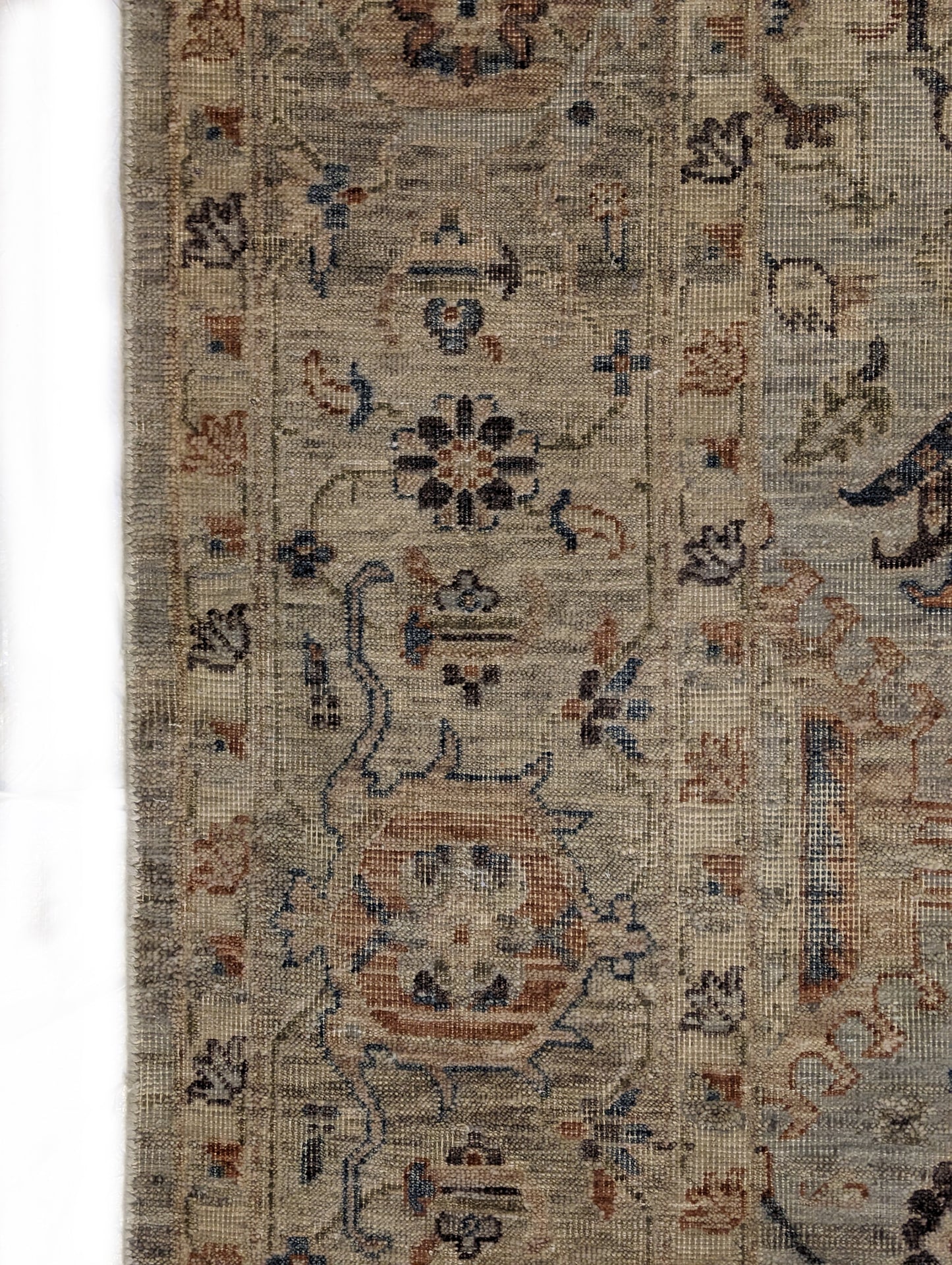 A hand-knotted wool rug with a traditional and coastal design in beige, blue, brown, and gold colors.