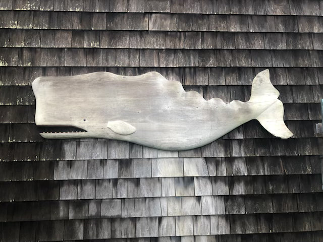 two hand-carved white whales hanging over a bed 