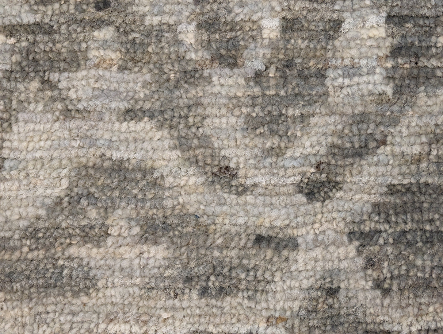 A hand-knotted wool rug with a subtle grey color palette, featuring intricate geometric patterns.