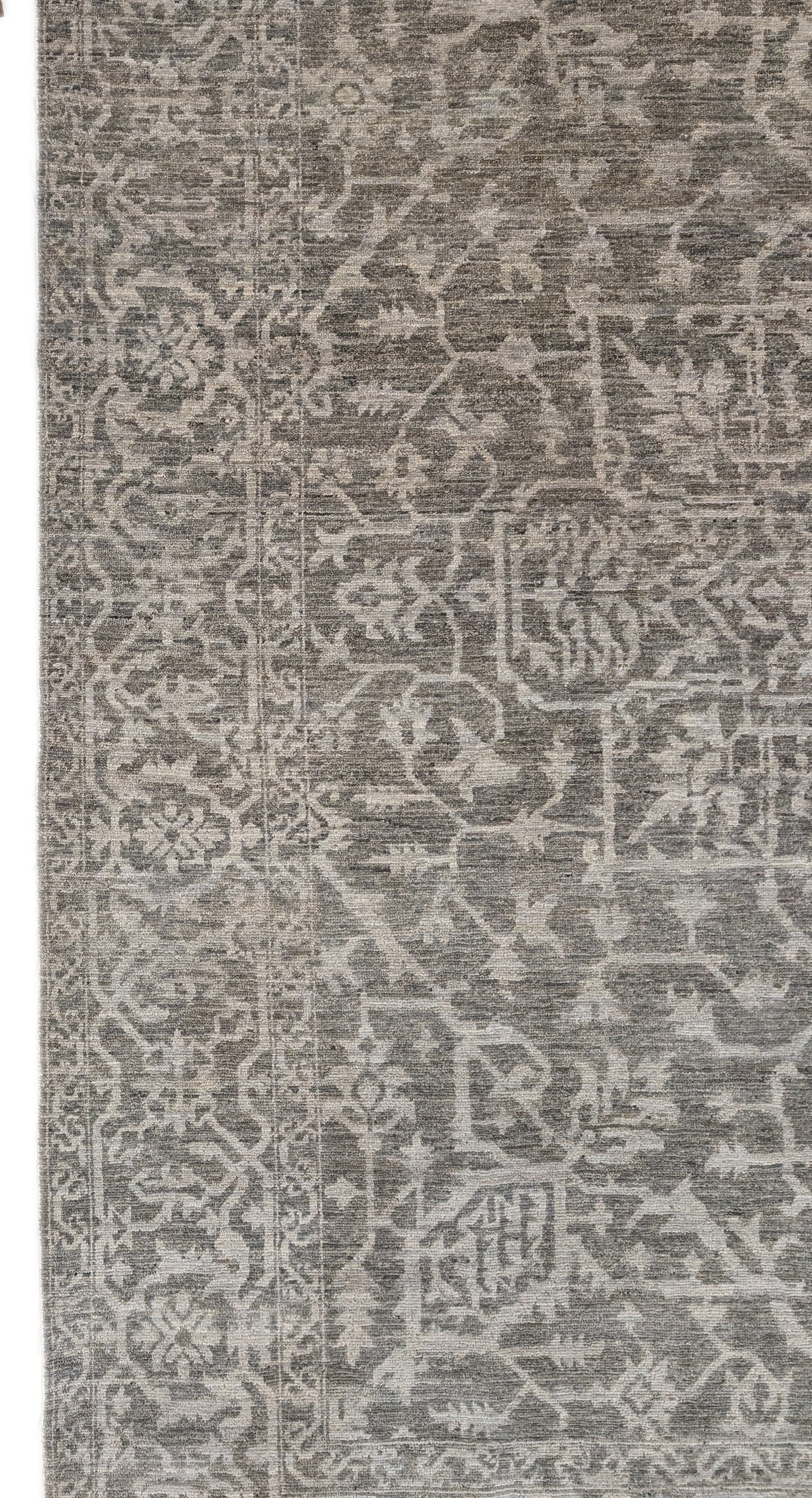 A hand-knotted wool rug with a subtle grey color palette, featuring intricate geometric patterns.
