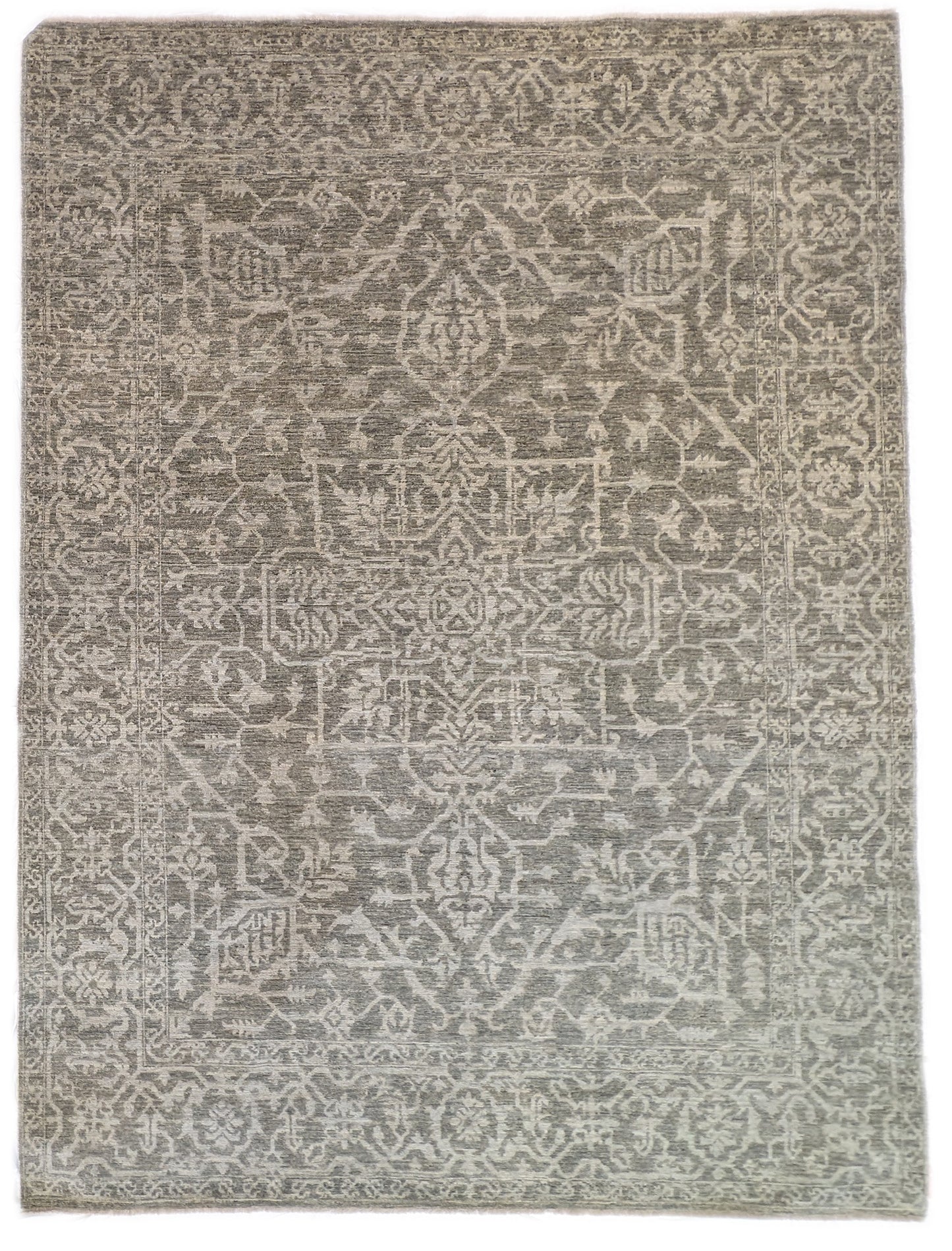 A hand-knotted wool rug with a subtle grey color palette, featuring intricate geometric patterns.