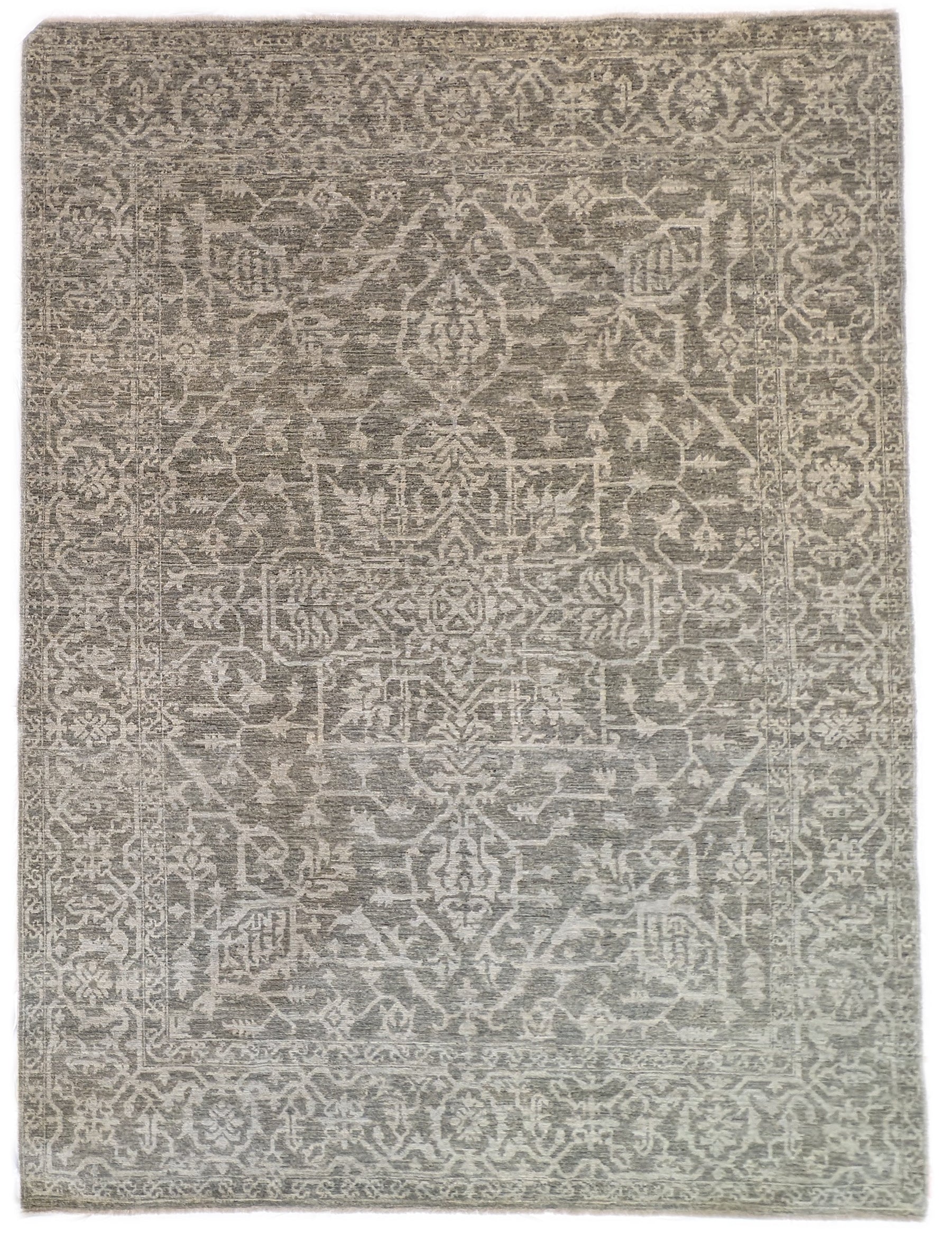 A hand-knotted wool rug with a subtle grey color palette, featuring intricate geometric patterns.