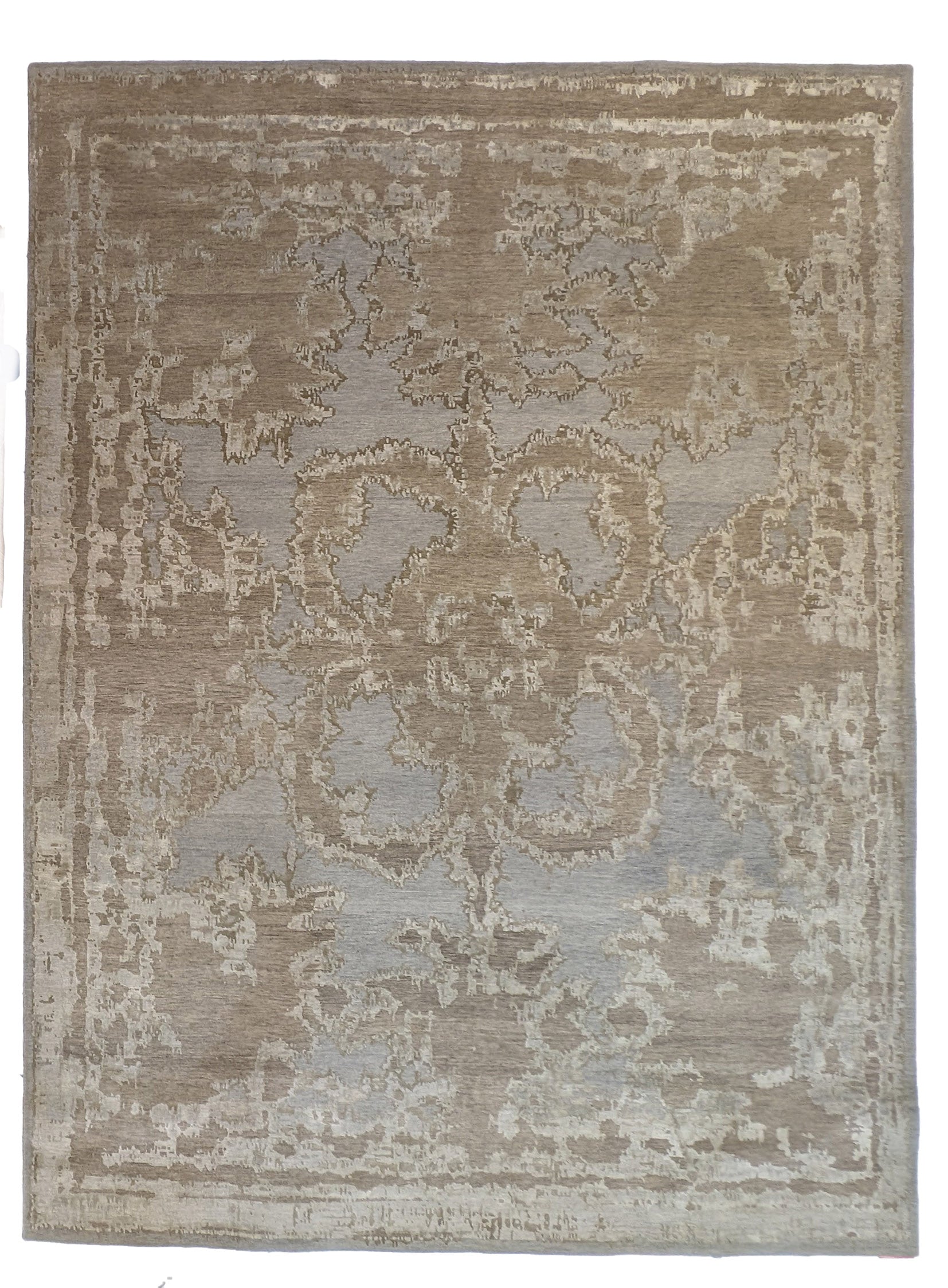 A hand-knotted wool and silk rug with a coastal-inspired design in shades of taupe, smokey blue, and soft grey.
