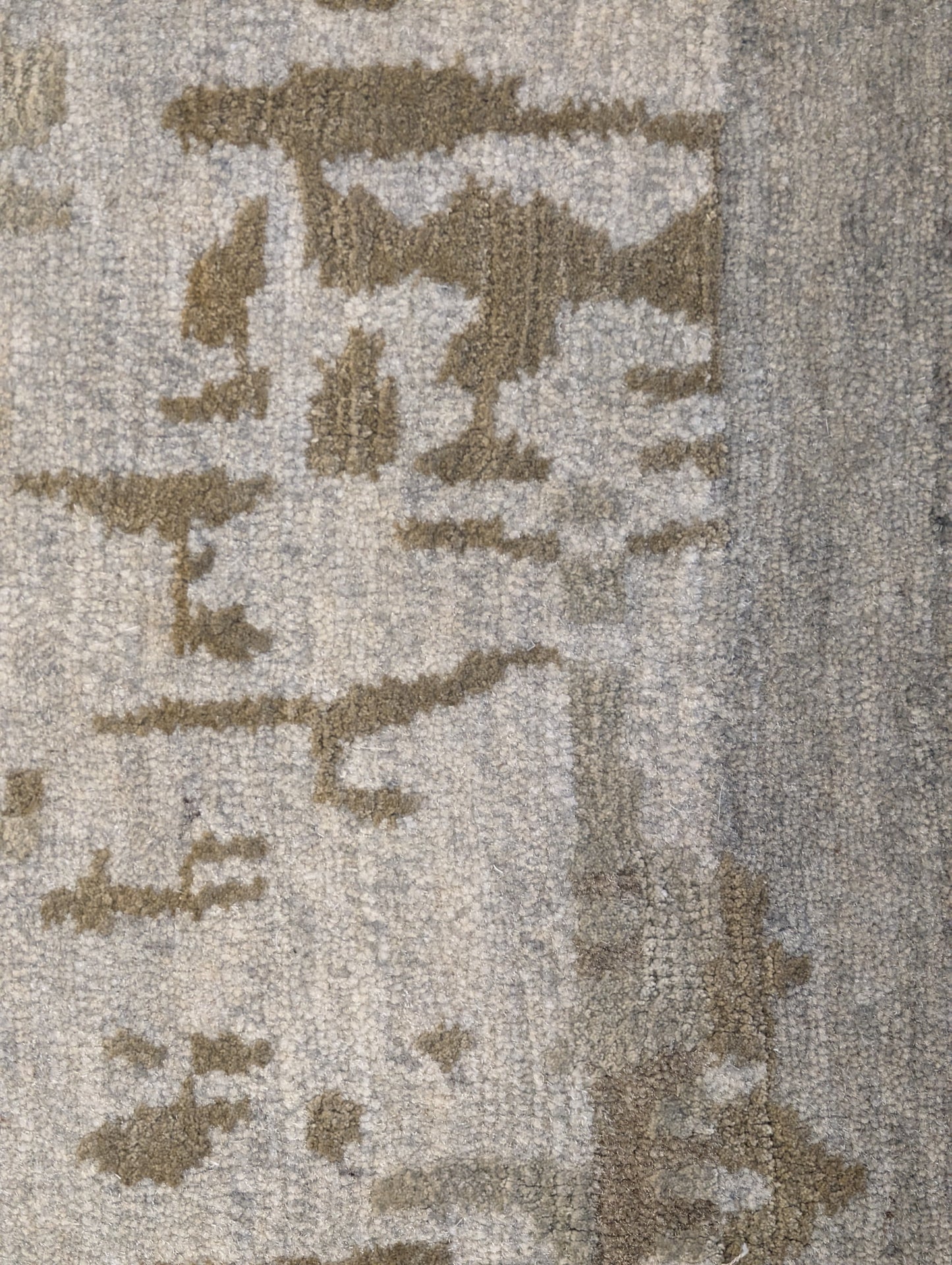A hand-knotted wool and silk rug with a coastal-inspired design in shades of taupe, smokey blue, and soft grey.