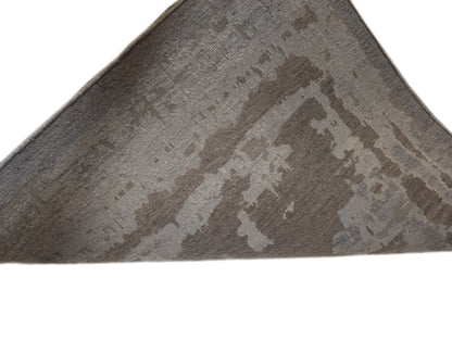 A hand-knotted wool and silk rug with a coastal-inspired design in shades of taupe, smokey blue, and soft grey.