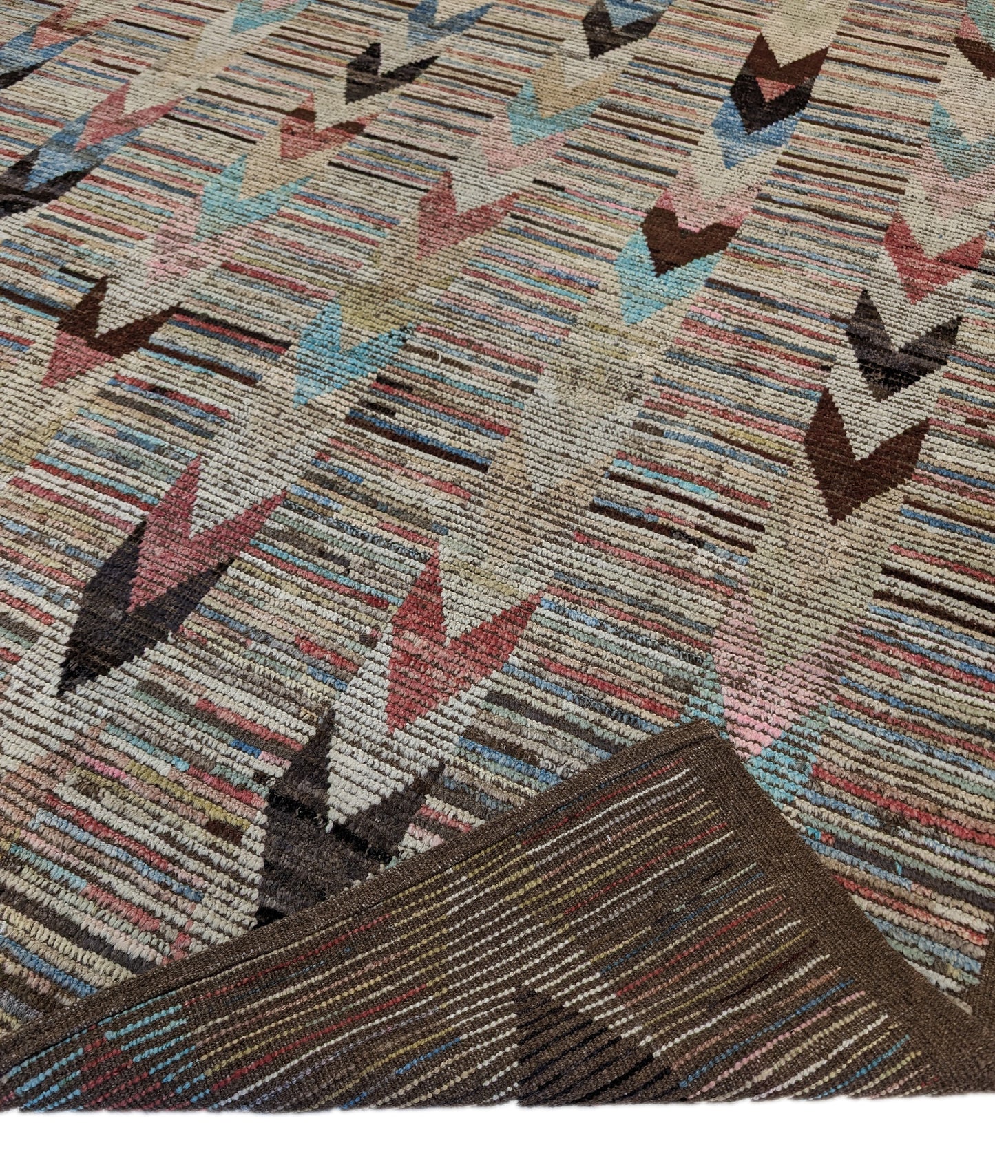 A hand-knotted wool rug with a coastal aesthetic in a plush design, featuring a mix of pink, red, yellow, blues, browns, and ivory colors.