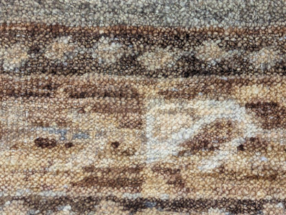 A hand-knotted wool rug with a geometric pattern in beige, blue, brown, and gold colors, showcasing a blend of traditional and contemporary design elements.