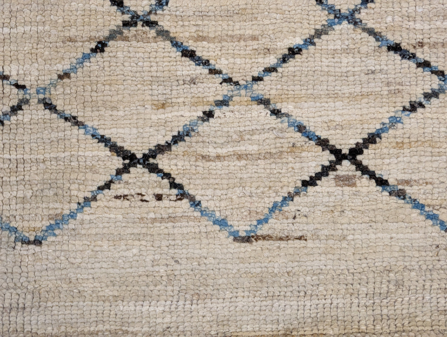 A hand-knotted wool rug with a geometric pattern in beige, brown, blue,  and gray tones, featuring a coastal aesthetic. Cozy pile. 