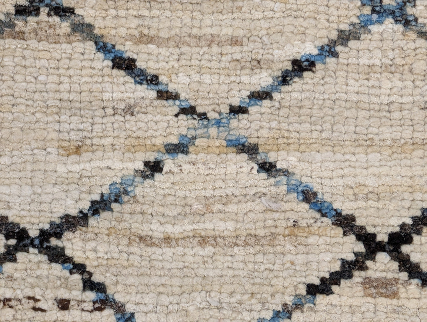 A hand-knotted wool rug with a geometric pattern in beige, brown, blue,  and gray tones, featuring a coastal aesthetic. Cozy pile. 
