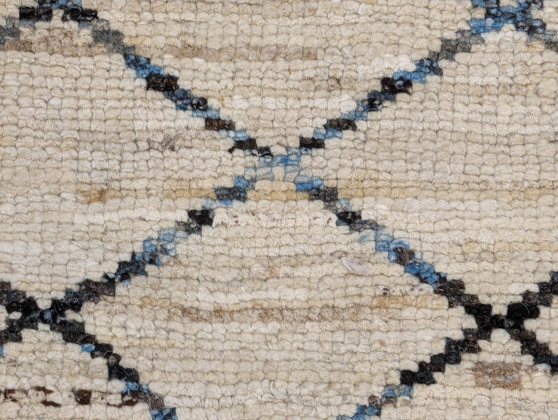 A hand-knotted wool rug with a geometric pattern in beige, brown, blue,  and gray tones, featuring a coastal aesthetic. Cozy pile. 
