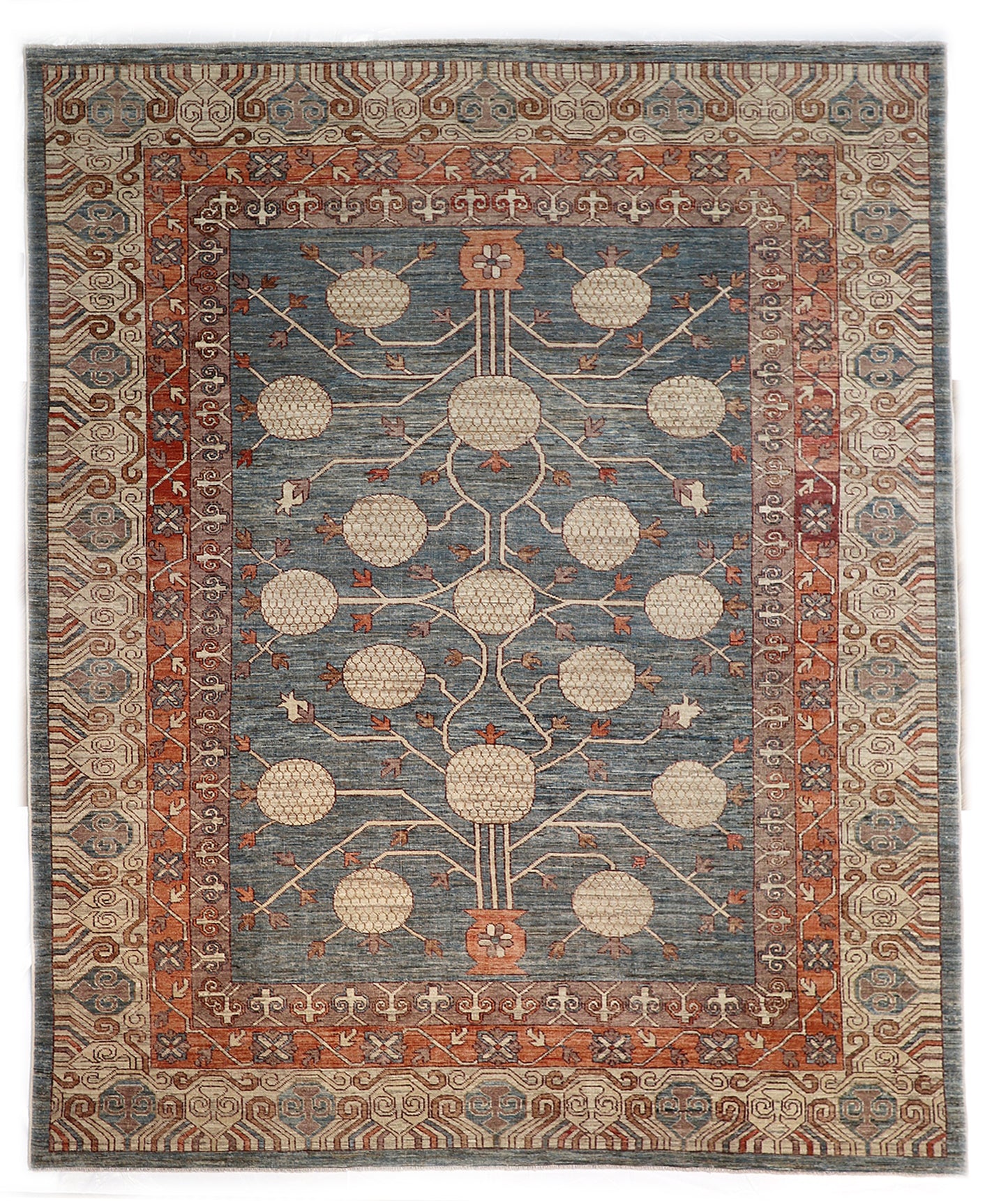 Hand-knotted decorative wool rug with a high pile in dusky ocean blue with sand, pebble gray, weathered red, and coral accents.