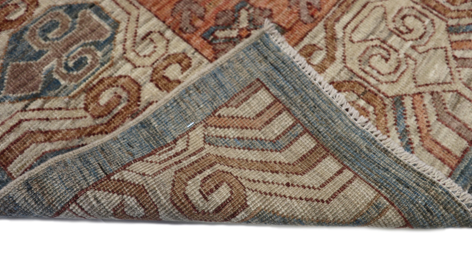 Hand-knotted decorative wool rug with a high pile in dusky ocean blue with sand, pebble gray, weathered red, and coral accents.