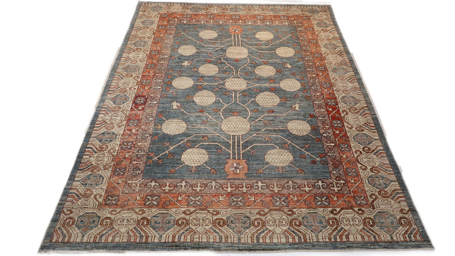 Hand-knotted decorative wool rug with a high pile in dusky ocean blue with sand, pebble gray, weathered red, and coral accents.