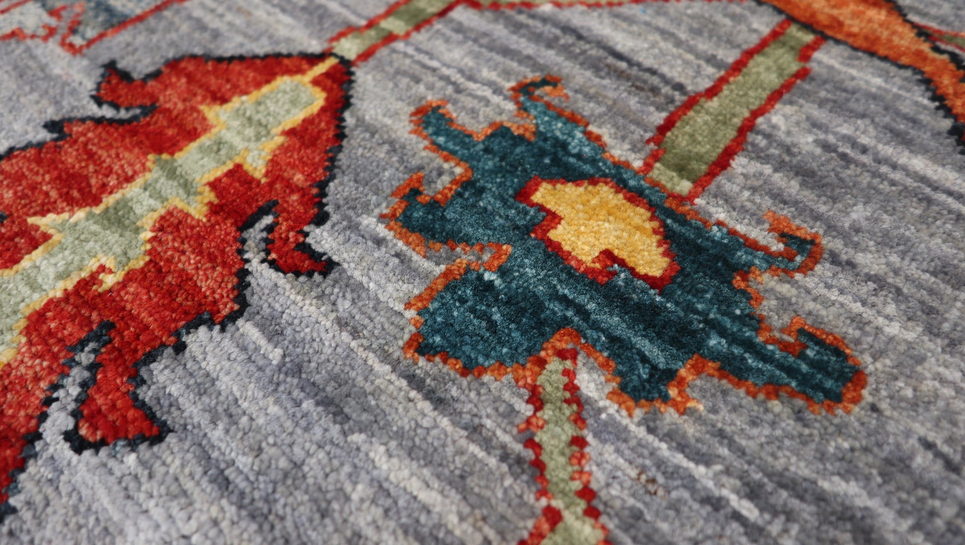 Transitional hand-knotted rug in muted gray-blue with faded coral red, soft orange, and sandy ochre accents.
