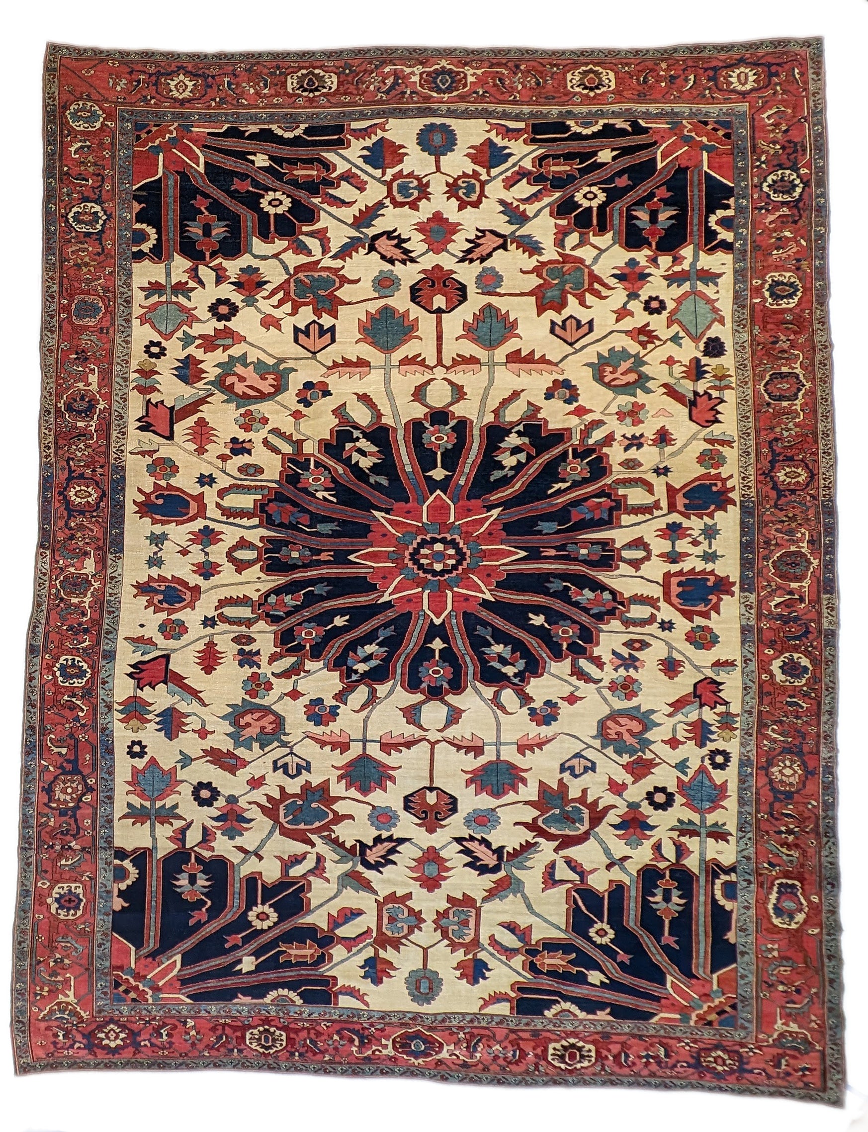 A hand-knotted wool rug with a traditional Serapi design, featuring a luxurious palette of ink blue, warm reds, green, pink, gold, blue, and ivory.