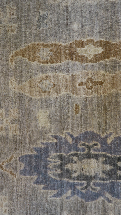 Hand-knotted wool rug in a traditional design featuring driftwood gray and sandy beige with sea glass blue and gold accents and a low pile.