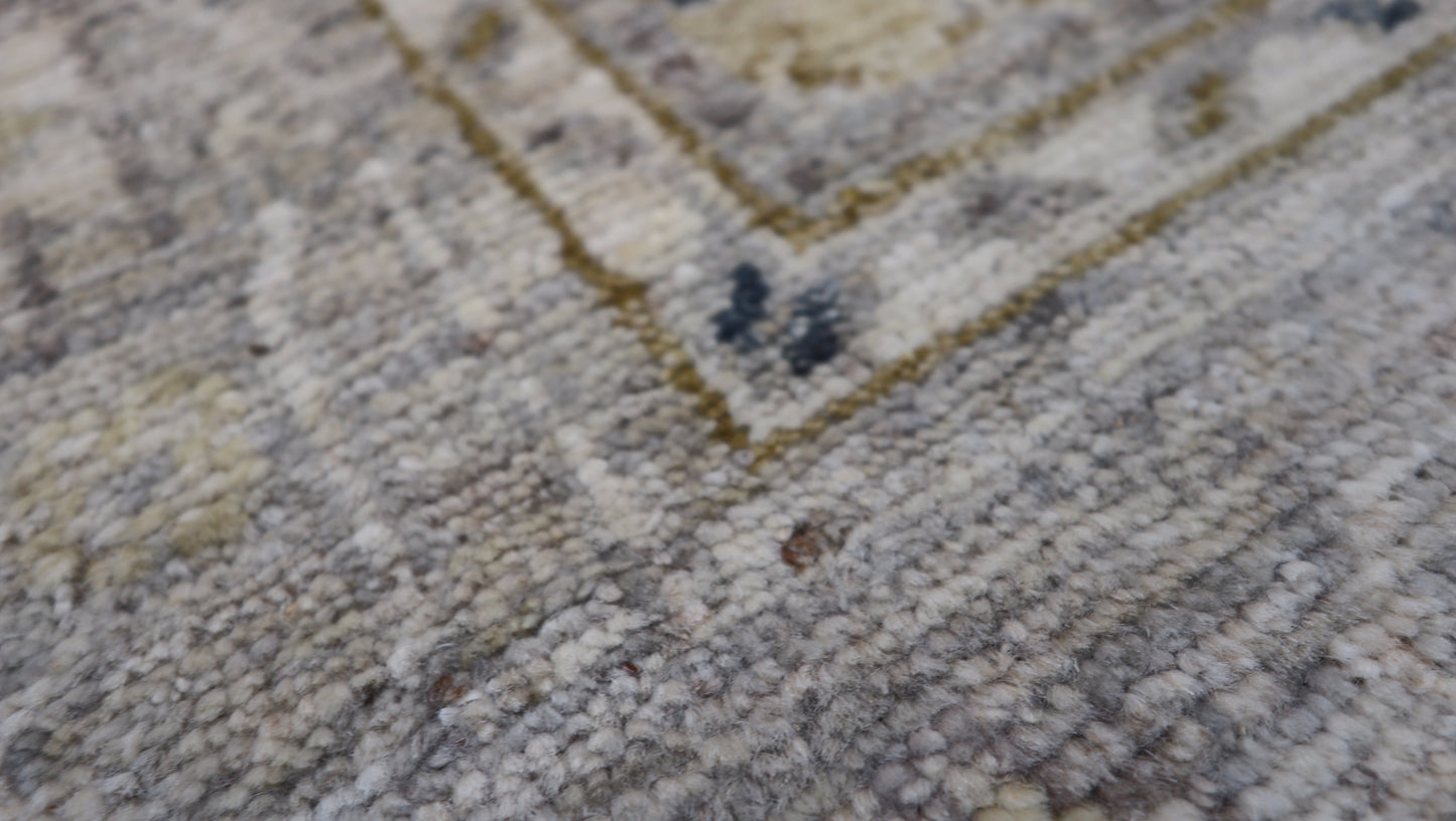 Hand-knotted wool rug with an antique finish in mist-gray, sand, and pale seagrass green with gold accents.