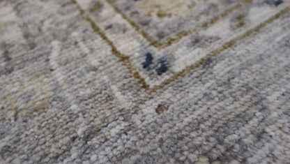Hand-knotted wool rug with an antique finish in mist-gray, sand, and pale seagrass green with gold accents.