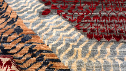 Hand-knotted intricate patterned rug in stormy sea gray and ocean blue with weathered red and stone accents.