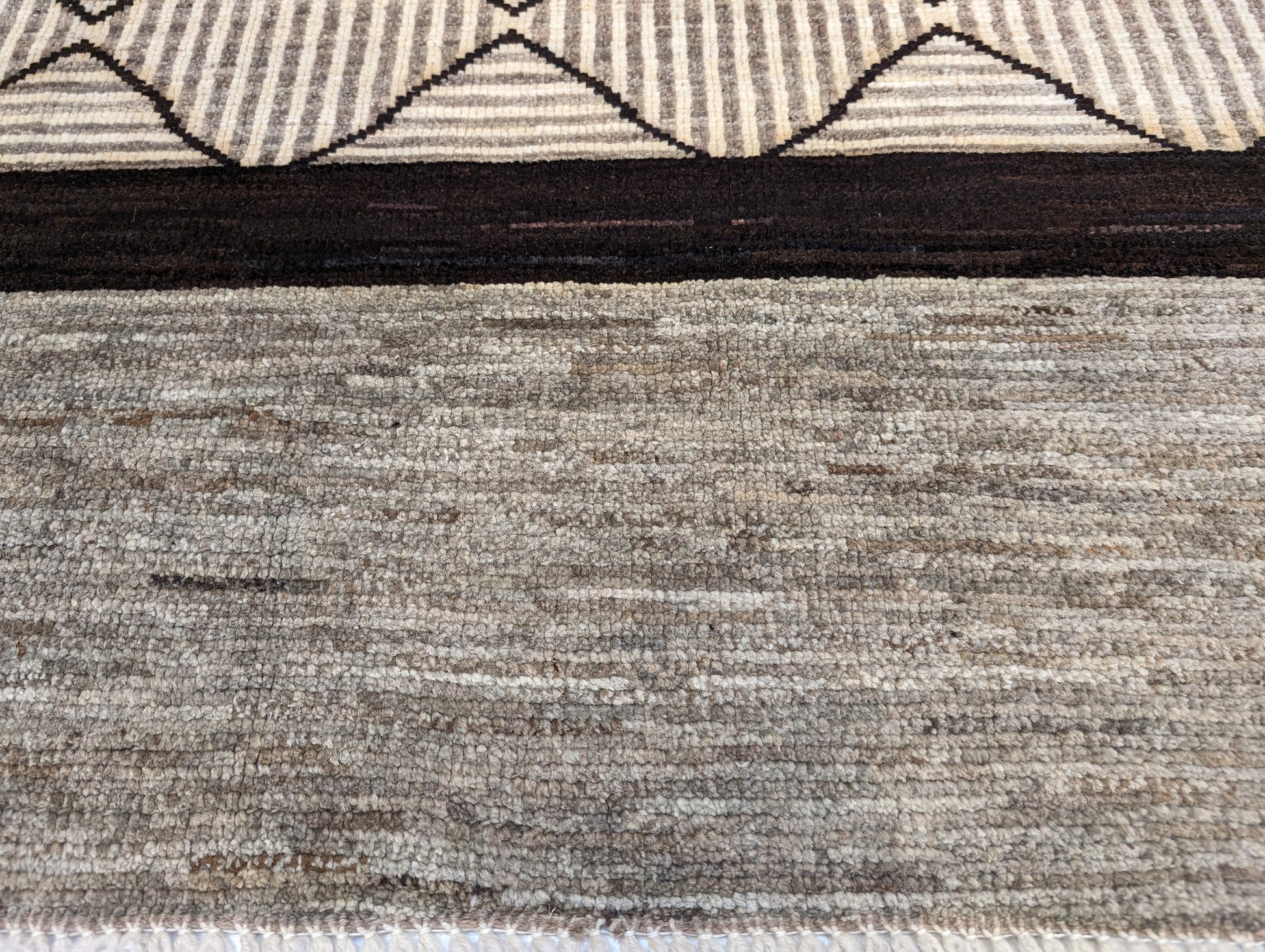 A hand-knotted wool rug with a geometric pattern in natural tones of beige, brown, and gray. Cozy pile. 