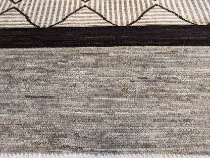 A hand-knotted wool rug with a geometric pattern in natural tones of beige, brown, and gray. Cozy pile. 