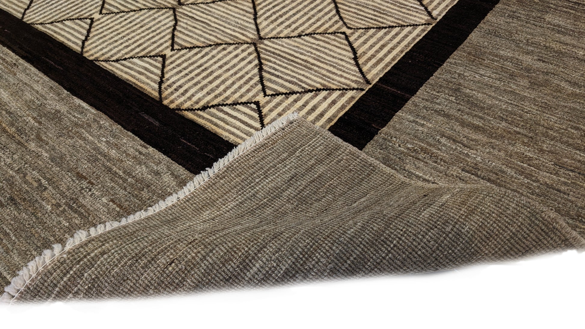A hand-knotted wool rug with a geometric pattern in natural tones of beige, brown, and gray. Cozy pile. 