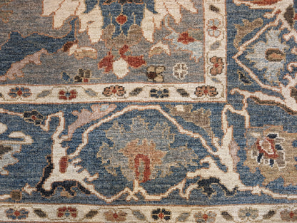 A hand-knotted wool rug with a traditional and contemporary design, featuring a rich palette of colors including slate grey, red, gold, pink, blue, green, and beige, and decorative border patterns.