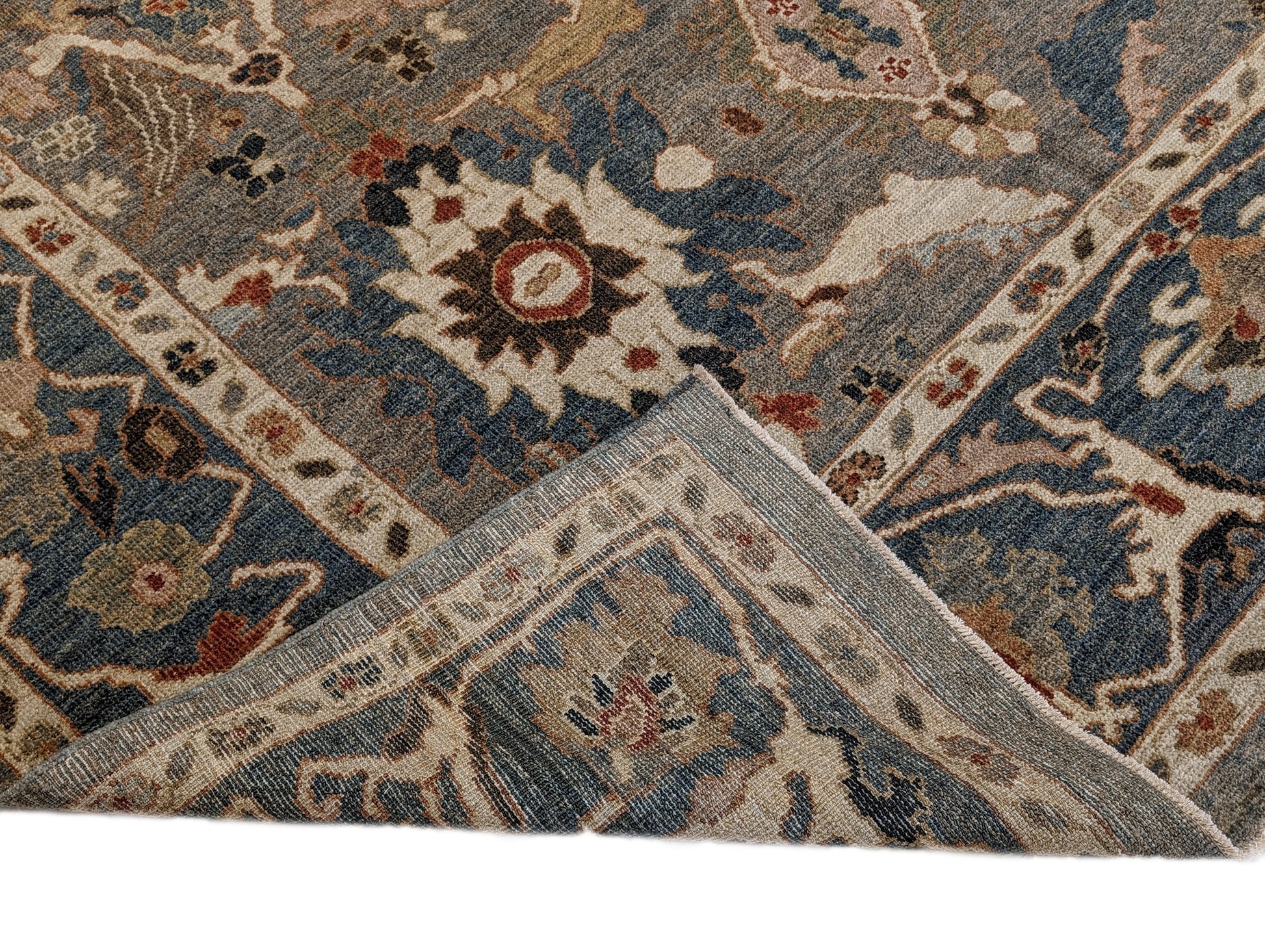 A hand-knotted wool rug with a traditional and contemporary design, featuring a rich palette of colors including slate grey, red, gold, pink, blue, green, and beige, and decorative border patterns.