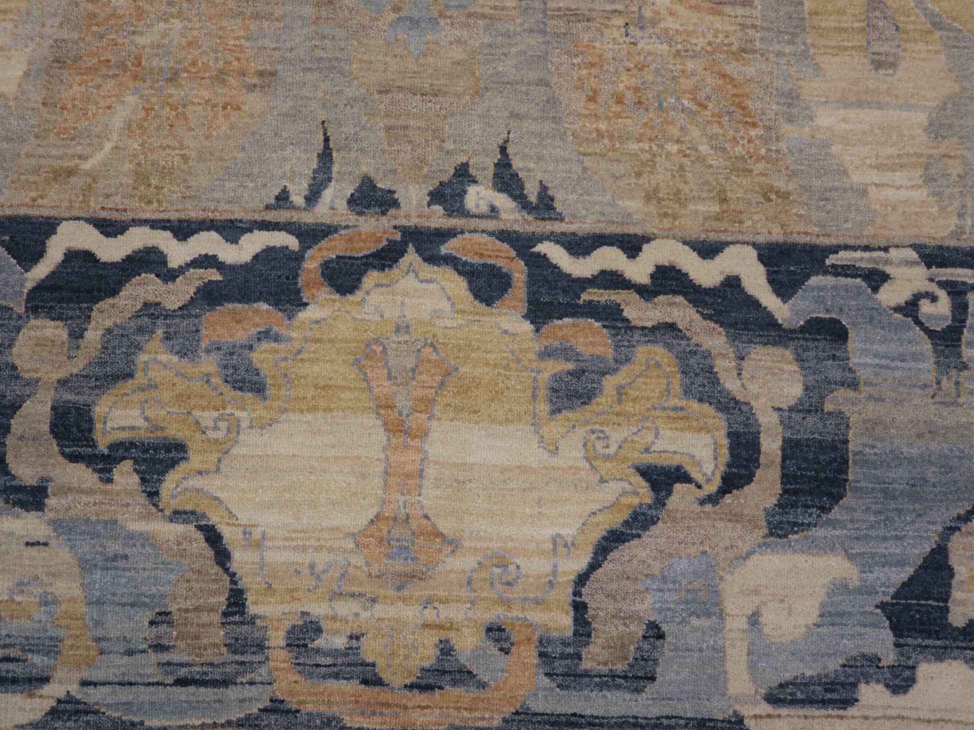 A hand-knotted wool rug with a coastal design featuring navy, ivory, sandy taupe, blue, peach, and yellow colors.