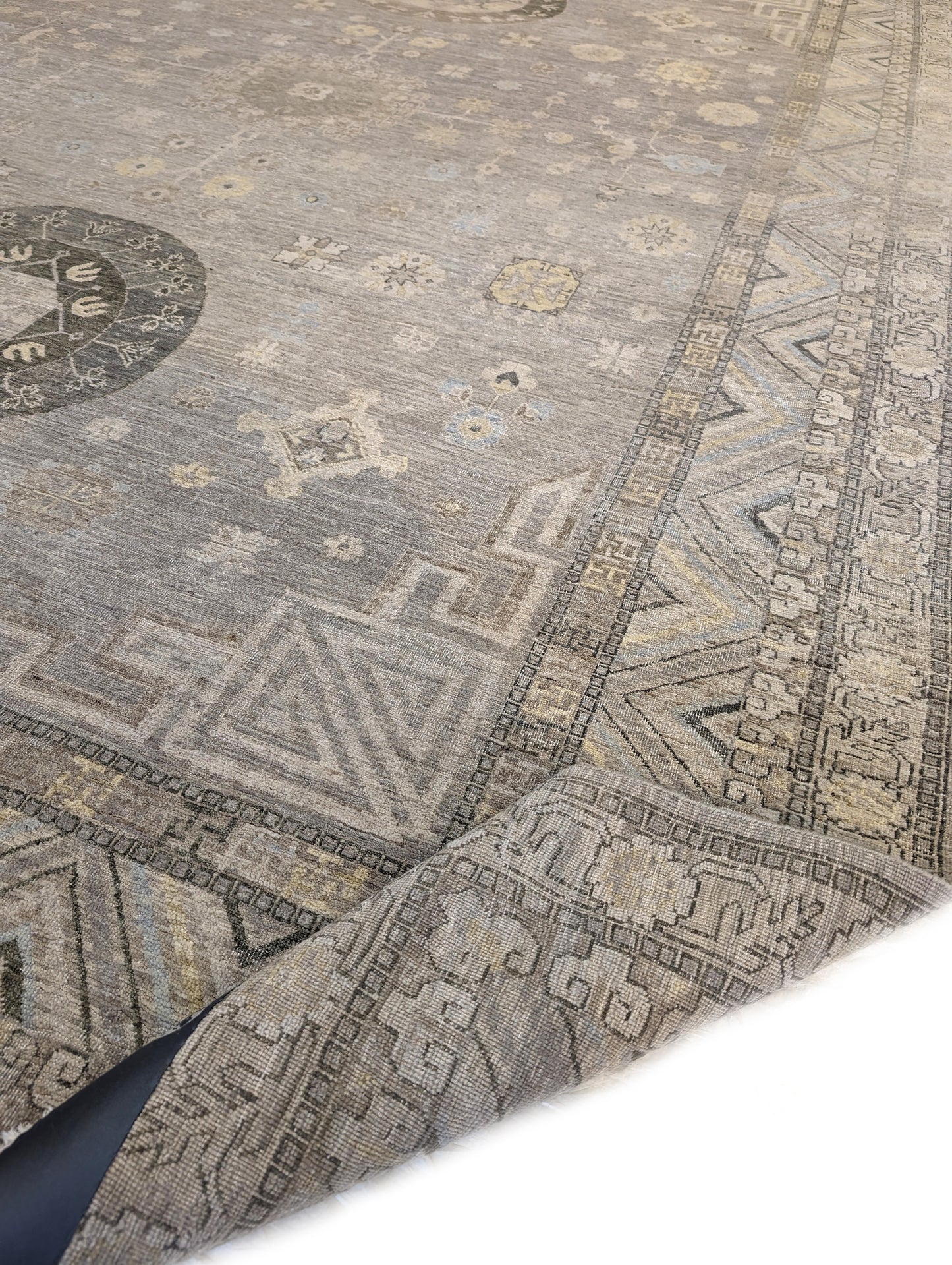 A hand-knotted wool rug with a coastal palette of sandy taupe, yellow, subtle grey, soft blue, and ivory, featuring traditional and contemporary geometric patterns.