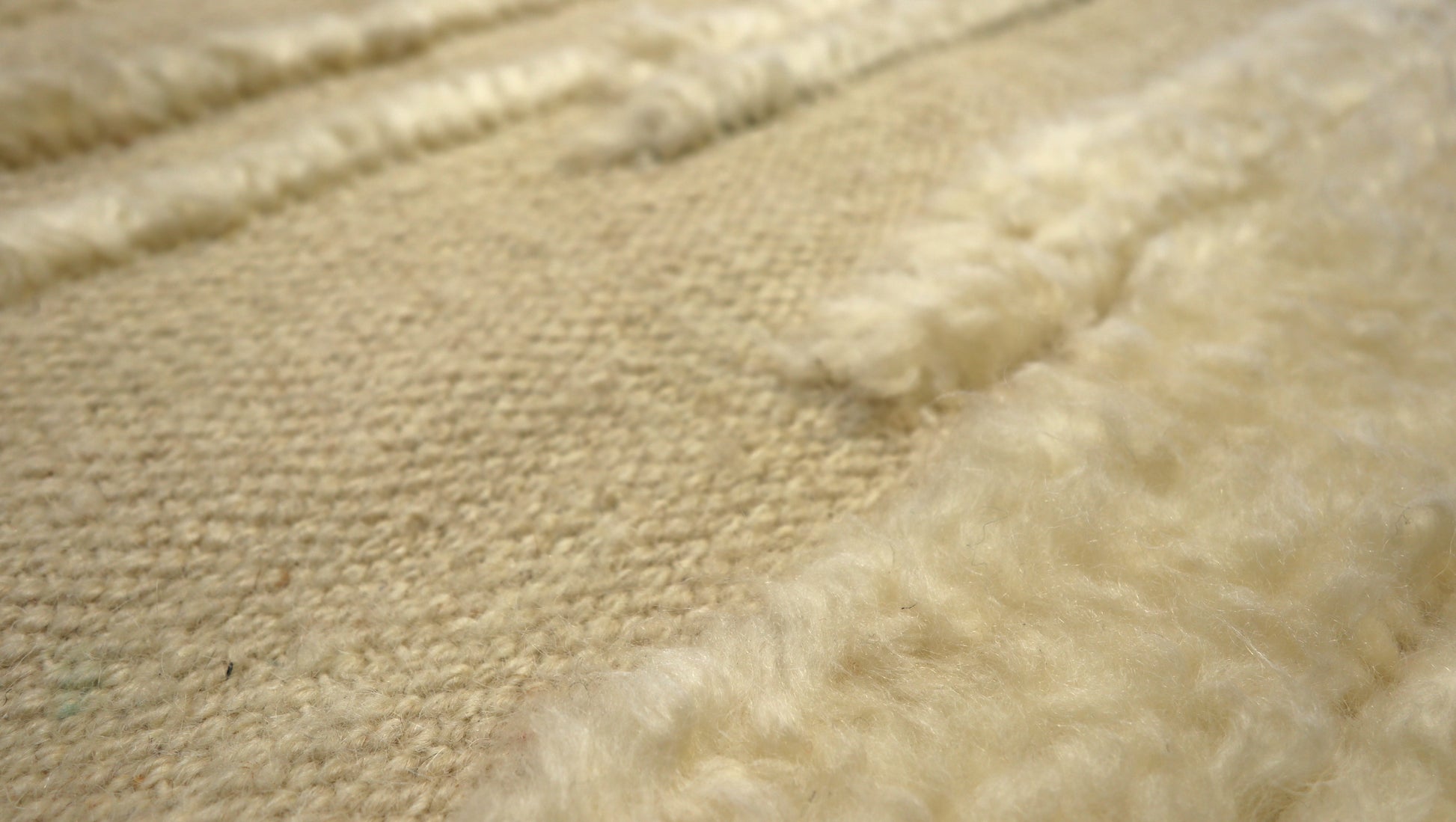 Hand-knotted high-low pile wool rug in natural undyed ivory and warm sandy beige with a large knot texture.