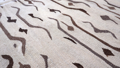 Hand-knotted wool kilim flatweave in sun-baked sand and earthy driftwood tones with deep brown accents