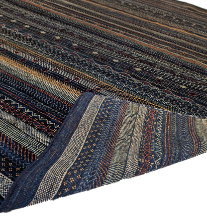 A hand-knotted wool rug with a geometric pattern in a variety of coastal hues including deep navy blue, red, warm orange, green, cheerful yellow, and soft ivory. Cozy pile. 