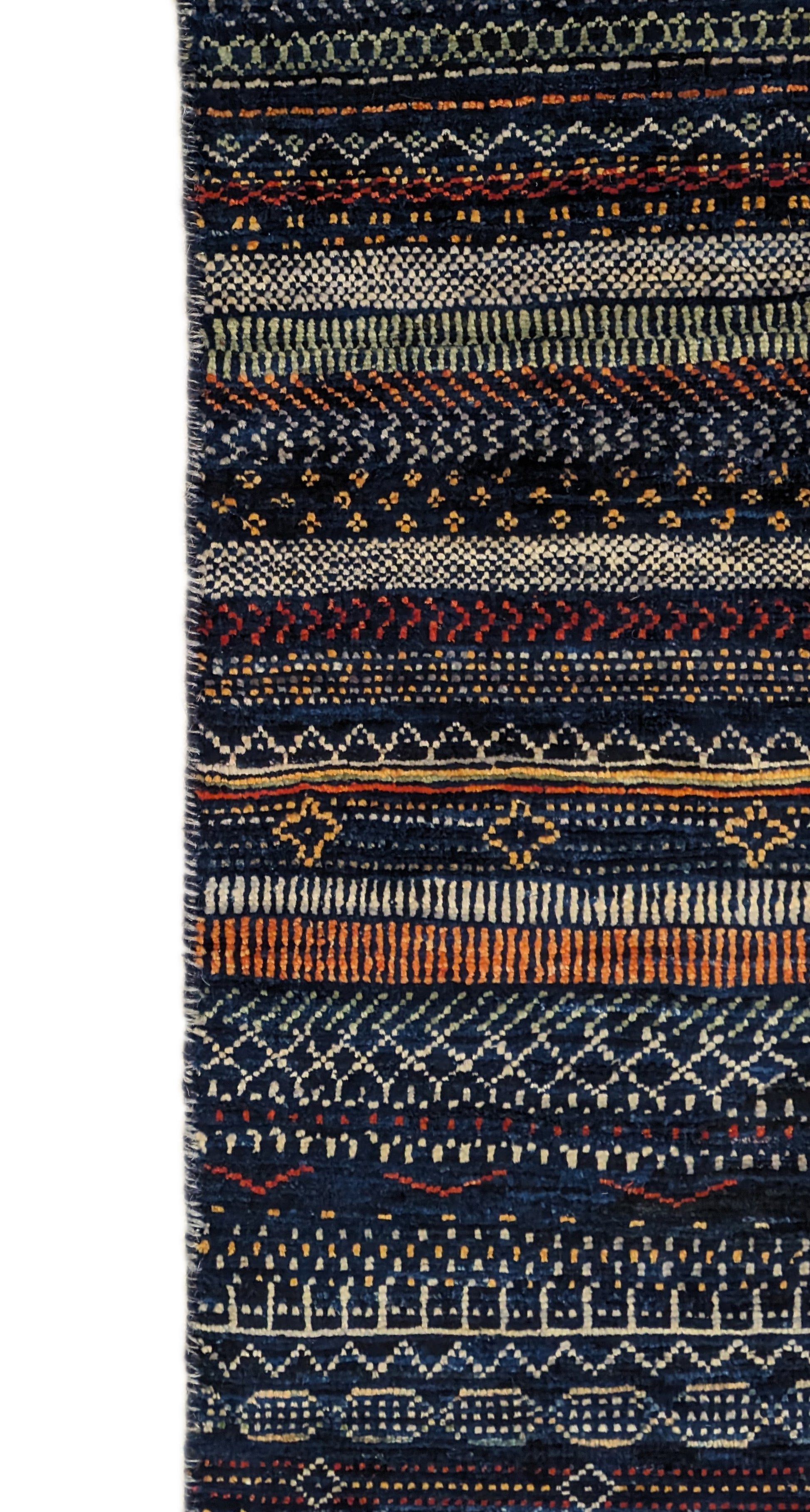 A hand-knotted wool rug with a geometric pattern in a variety of coastal hues including deep navy blue, red, warm orange, green, cheerful yellow, and soft ivory. Cozy pile. 