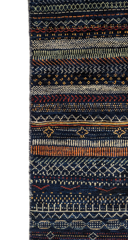 A hand-knotted wool rug with a geometric pattern in a variety of coastal hues including deep navy blue, red, warm orange, green, cheerful yellow, and soft ivory. Cozy pile. 
