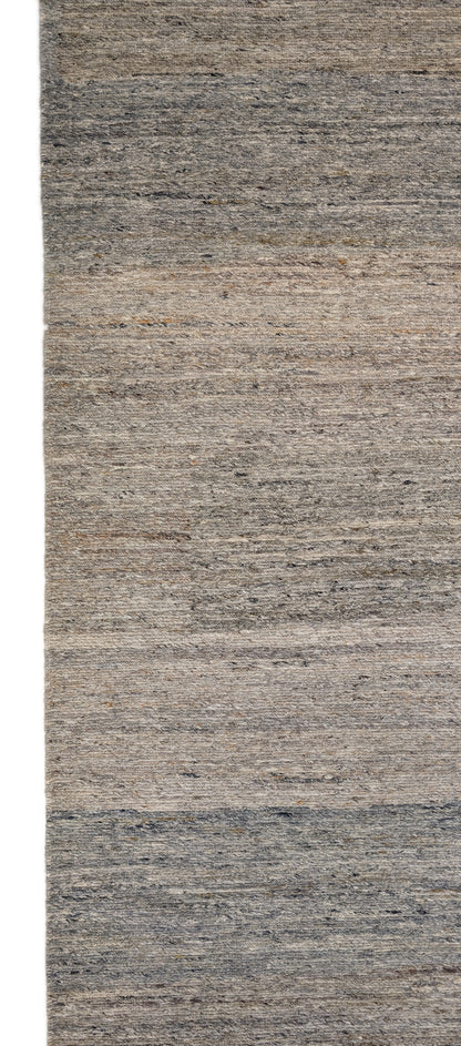 A hand-knotted wool rug with a coastal-inspired design in shades of light blue, beige, ivory, and brown. Cozy pile. 