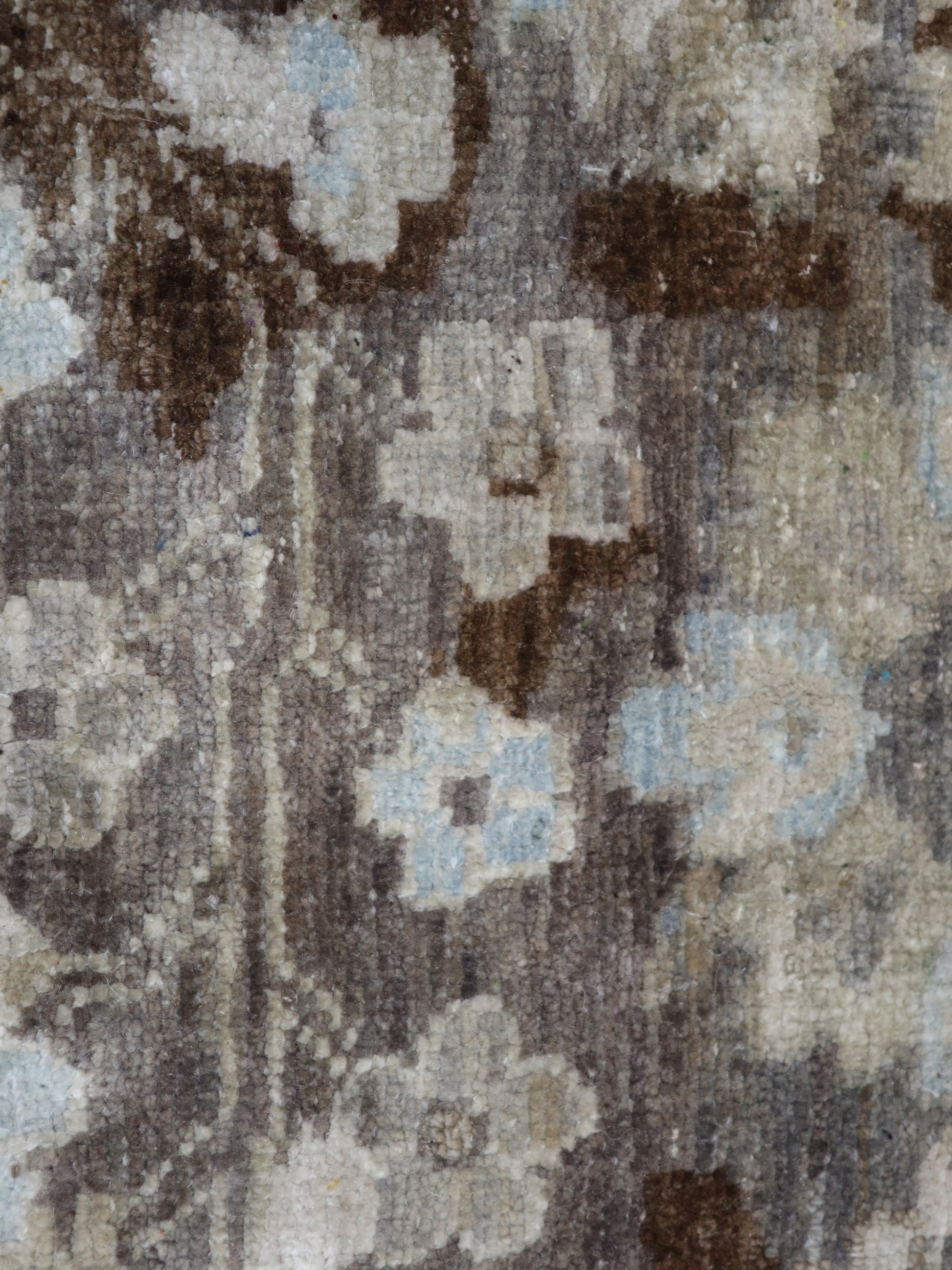 A hand-knotted silk and wool rug featuring a traditional and contemporary coastal design with natural tones of brown, taupe, light blue, grey, and ivory.