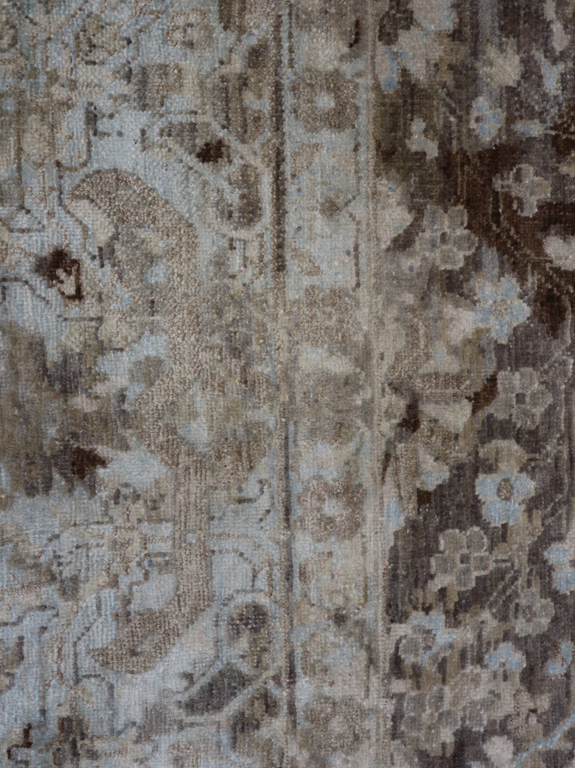 A hand-knotted silk and wool rug featuring a traditional and contemporary coastal design with natural tones of brown, taupe, light blue, grey, and ivory.