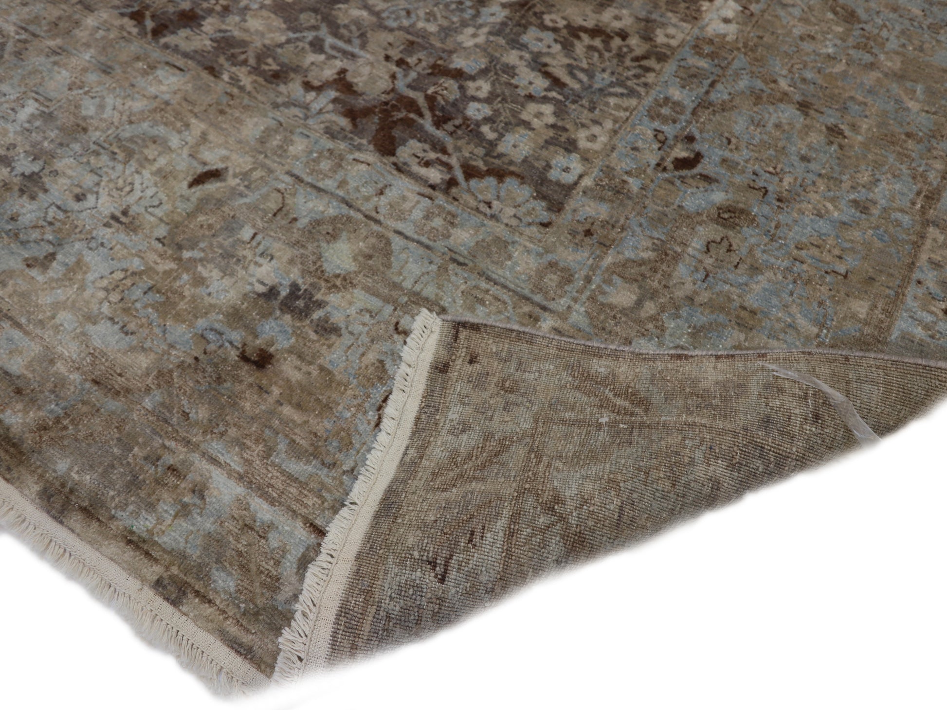 A hand-knotted silk and wool rug featuring a traditional and contemporary coastal design with natural tones of brown, taupe, light blue, grey, and ivory.