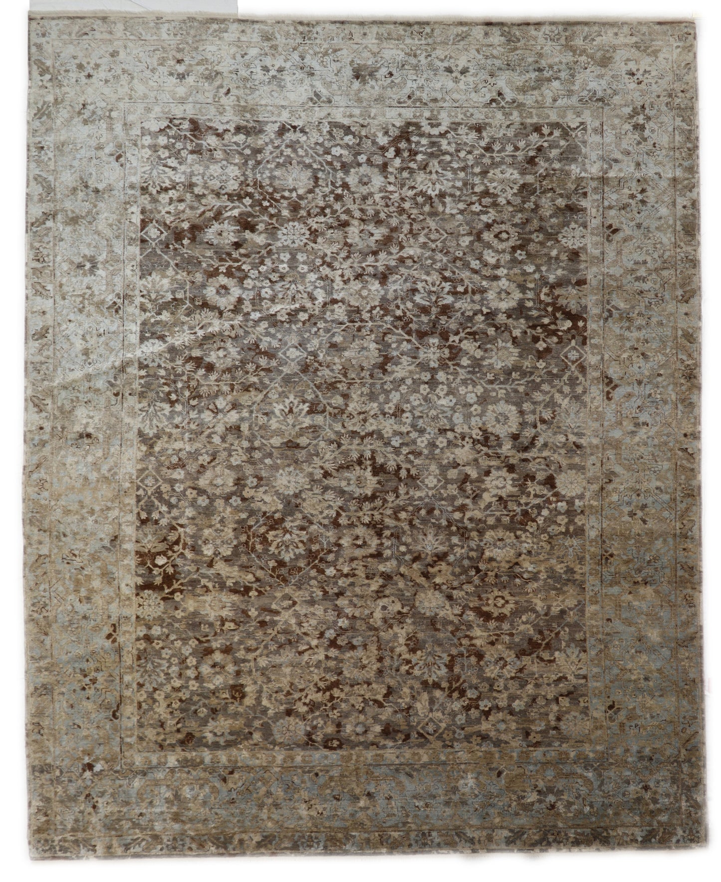 A hand-knotted silk and wool rug featuring a traditional and contemporary coastal design with natural tones of brown, taupe, light blue, grey, and ivory.