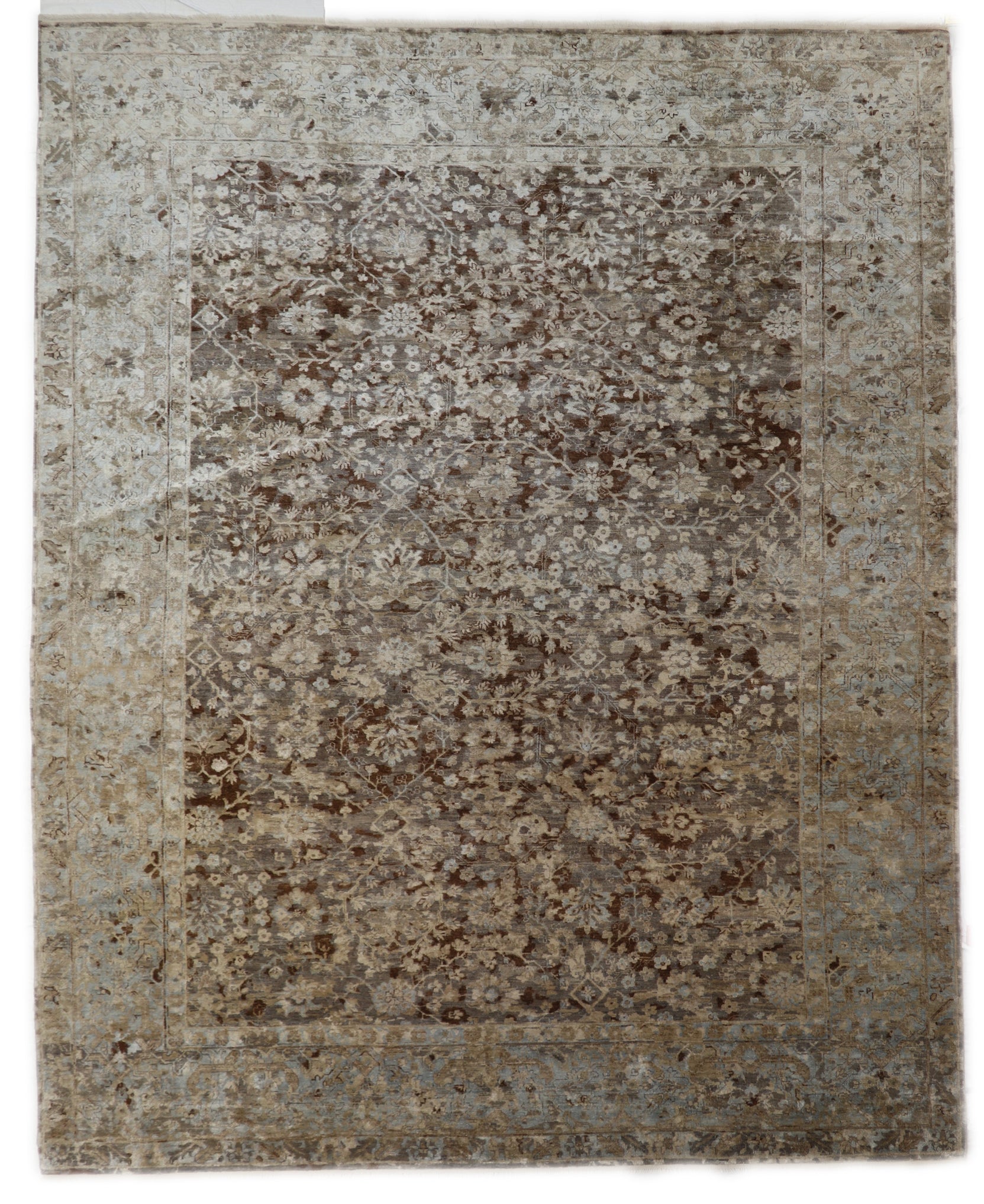 A hand-knotted silk and wool rug featuring a traditional and contemporary coastal design with natural tones of brown, taupe, light blue, grey, and ivory.