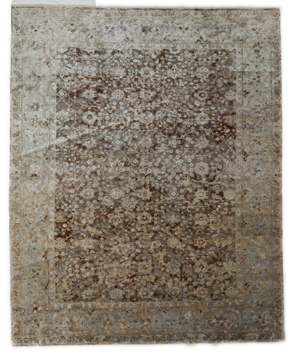 A hand-knotted silk and wool rug featuring a traditional and contemporary coastal design with natural tones of brown, taupe, light blue, grey, and ivory.