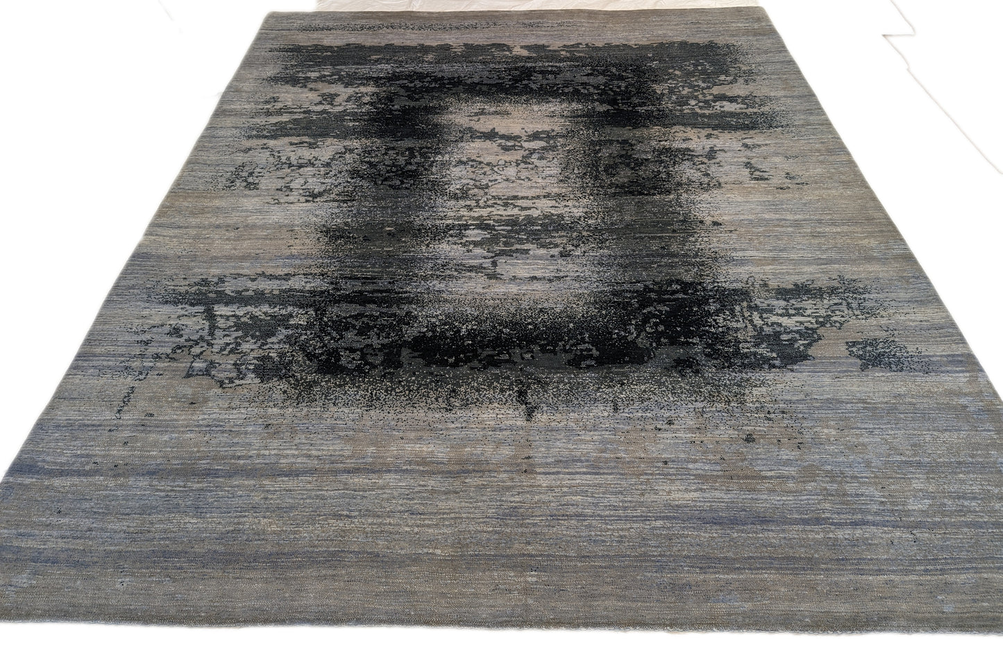 A hand-knotted rug with a serene coastal aesthetic featuring shades of gray, blue, and green, and a unique hand-knotted design. Cozy wool and luxurious silk. 