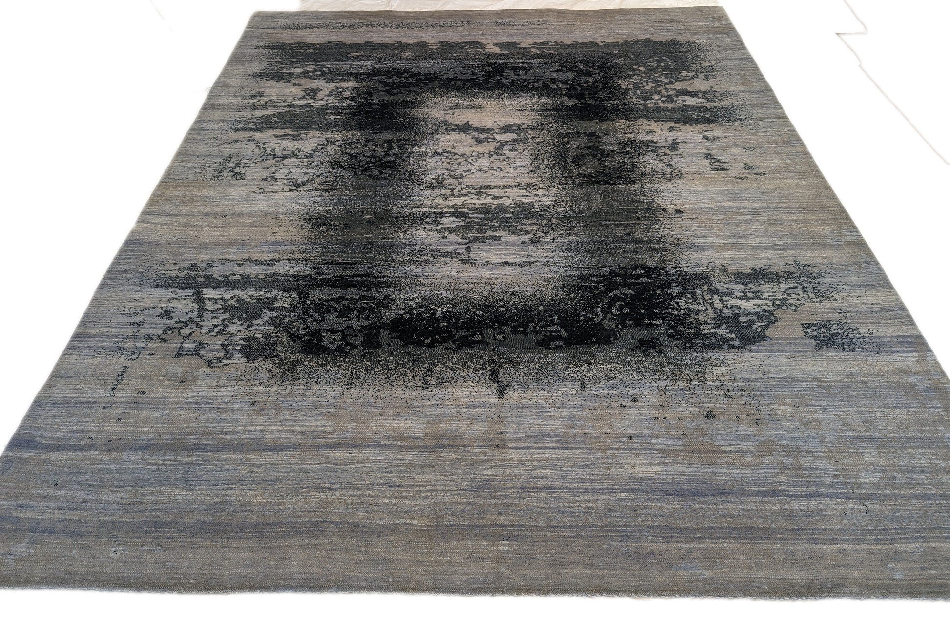 A hand-knotted rug with a serene coastal aesthetic featuring shades of gray, blue, and green, and a unique hand-knotted design. Cozy wool and luxurious silk. 