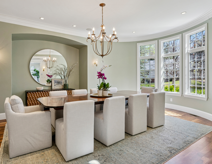 Dining room with a wooden table, white chairs, and a chandelier. The space is anchored by a cozy rug that perfectly unifies the décor.